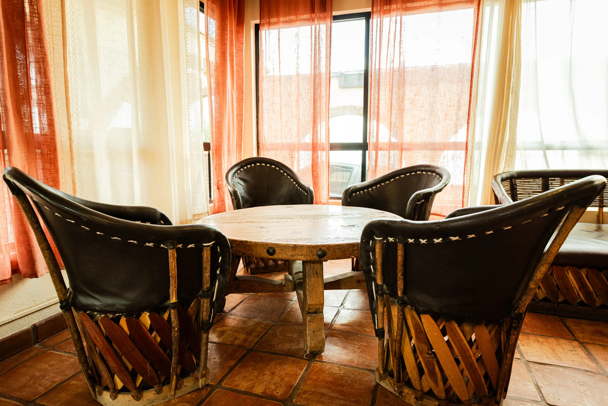 Round dining table and woven chairs beside curtained windows at Baja Rehab
