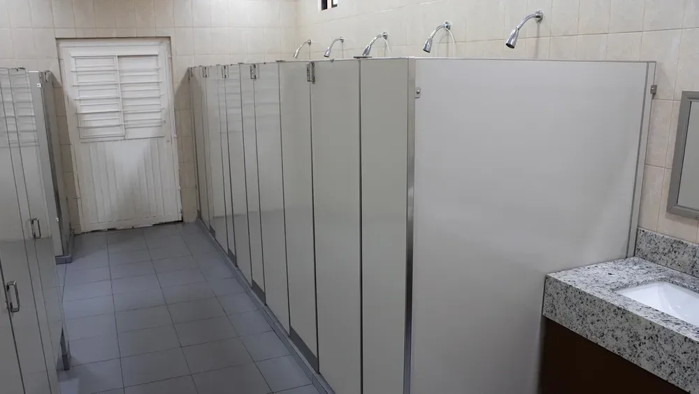 Communal shower area with gray privacy partitions and tiled floor