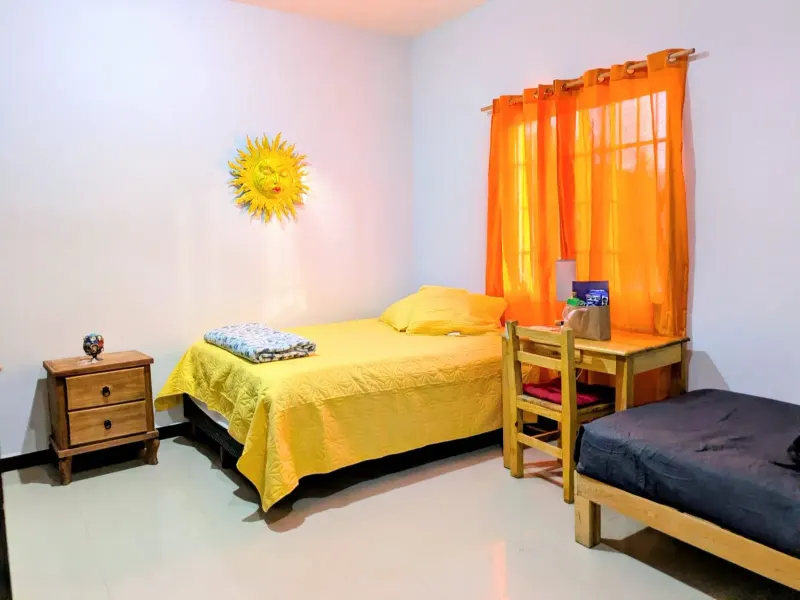 Bedroom with yellow and dark bedding, a wooden desk and orange curtains