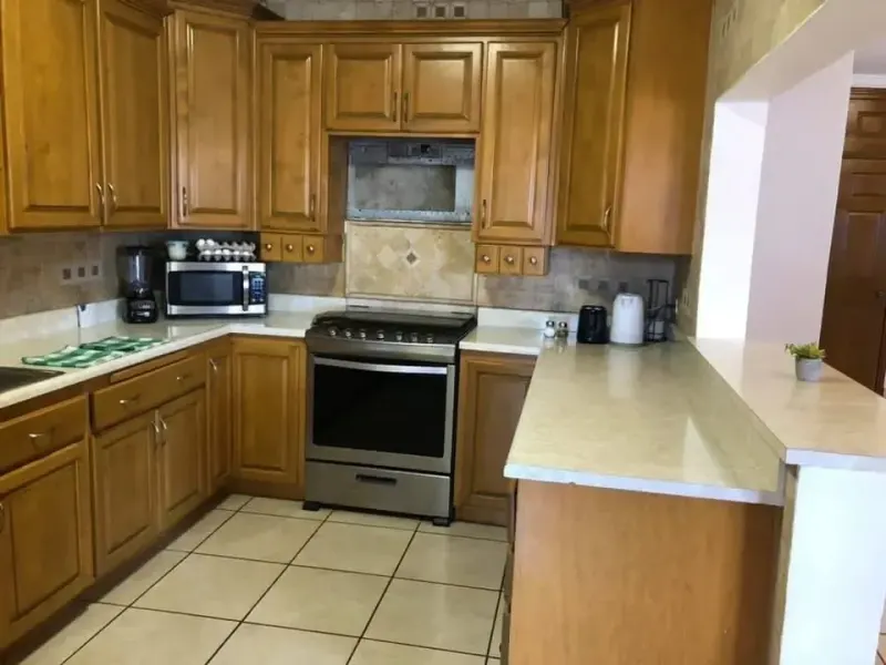 Empty kitchen with wooden cupboards, stove, microwave and coffee maker