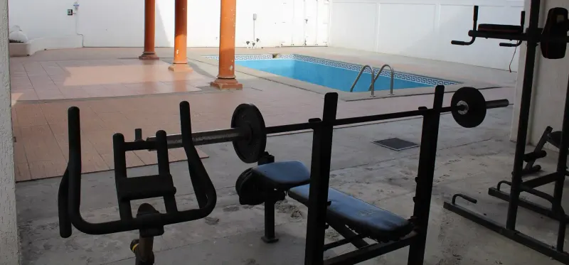Exercise equipment and a weight bench beside the courtyard swimming pool