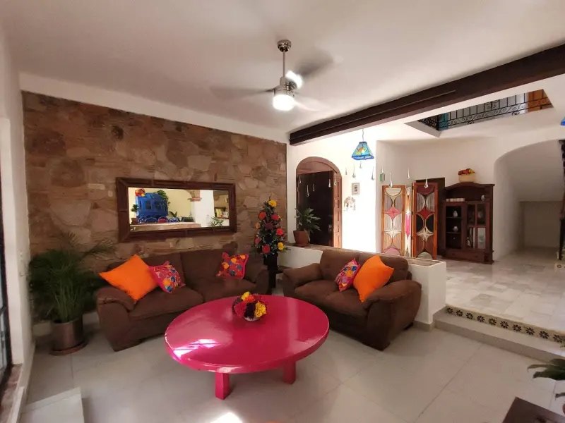 Living room with two brown sofas, bright cushions and round pink coffee table