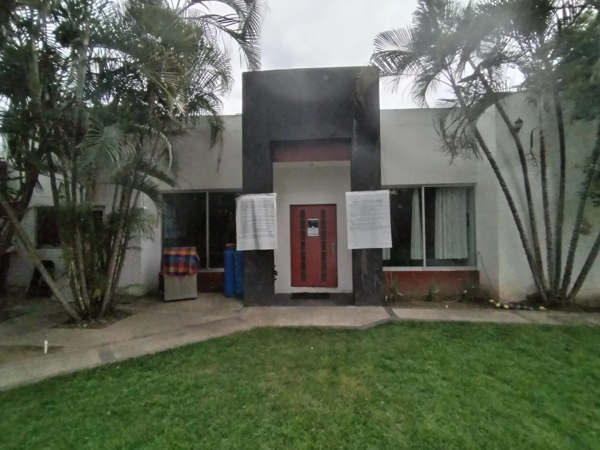 Residence exterior with a red door, large windows and palms