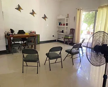 Empty room with chairs, a table, shelving and a floor fan