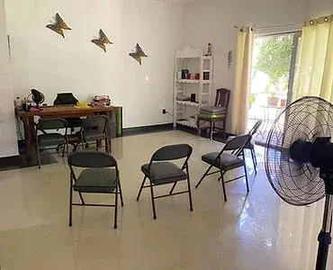 Empty room with chairs, a table, shelving and a floor fan
