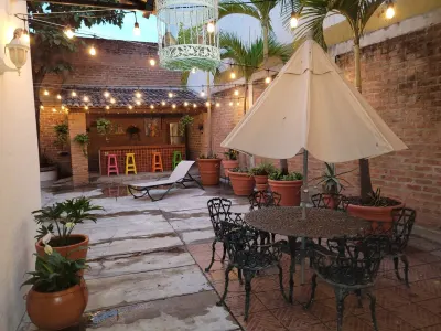 Brick courtyard with patio dining table, umbrella, lounge chair, potted plants and string lights