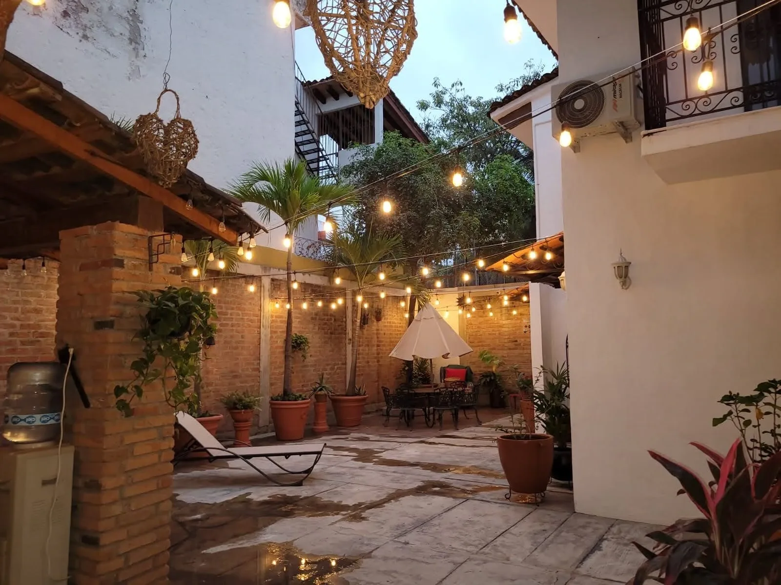 Courtyard at dusk with string lights, plants and a covered patio seating area