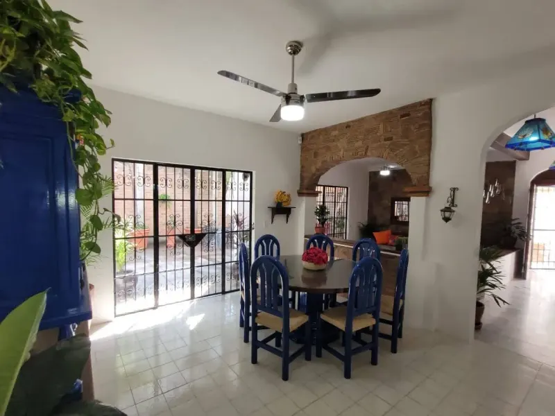 Dining room with blue wooden chairs and glass doors facing the courtyard