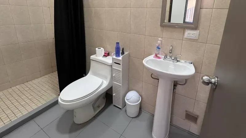 Tiled bathroom with toilet, sink and shower area
